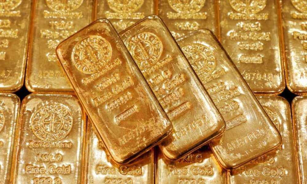 Gold slips off 2-week peak as dollar edges higher